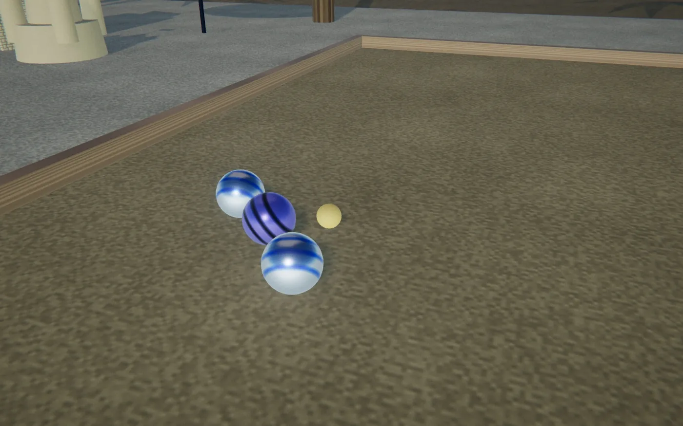 Close-up in the sand: three boules lying right next to the small yellow jack